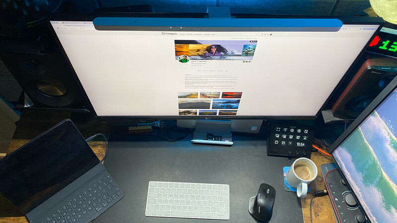 Photographer's desk setup with monitor displaying portfolio website, keyboard, mouse, and coffee cup
