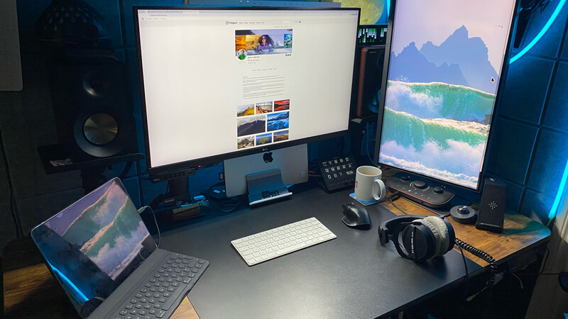 Photographer's workspace with multiple monitors displaying landscape imagery and a professional camera