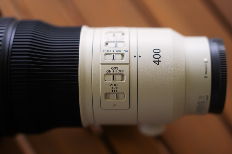 White telephoto lens barrel showing 400mm focal length and control buttons for autofocus and image stabilization