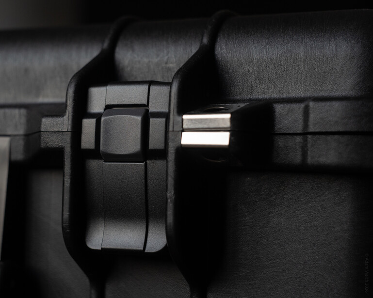 Close-up of a black camera holster or carrying case mounted on a tactical belt or strap