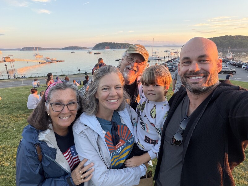 Family group photo shot on an iPhone at sunset, with the people and the harbor behind them all sharply in focus