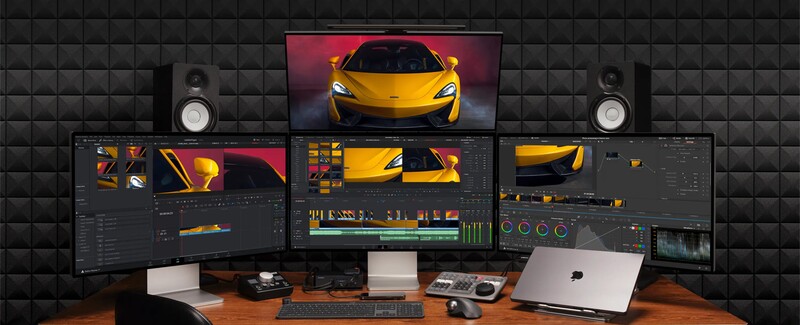 Professional video editing and color grading workstation with multi-monitor setup displaying yellow sports car footage