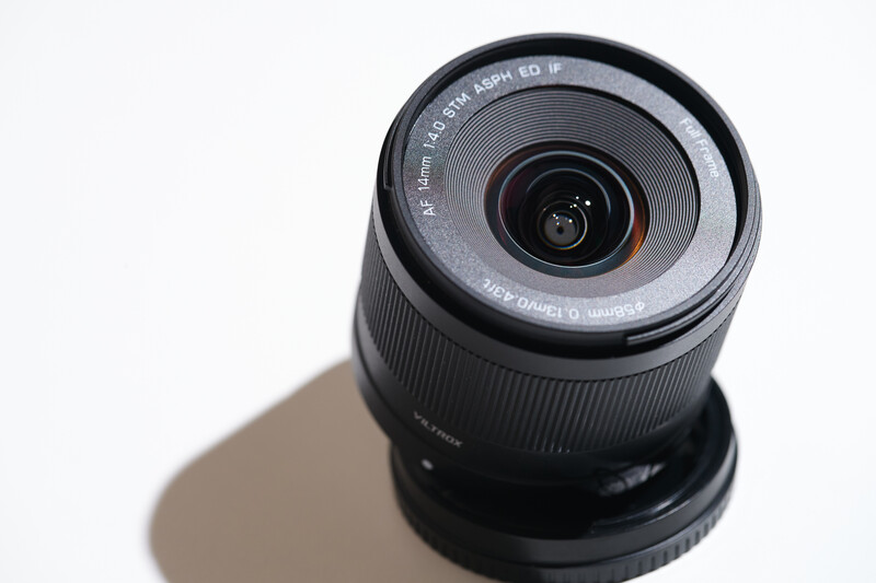Wide-angle zoom lens with black barrel and focus ring, shot from above against white background