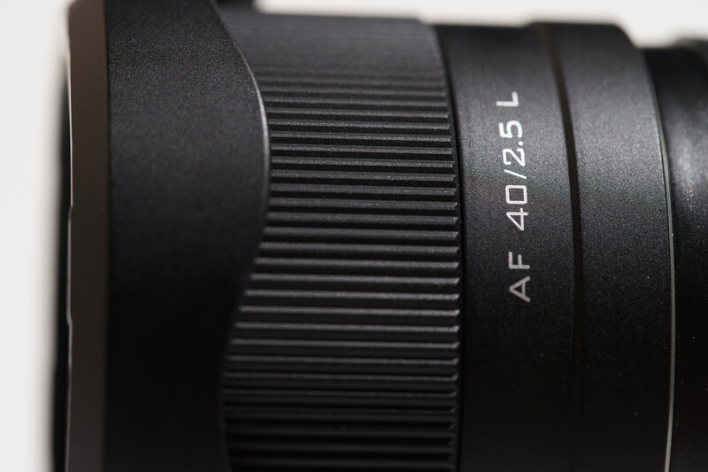 Close-up of a black camera lens showing AF 40D 2.5 aperture marking and focus ring