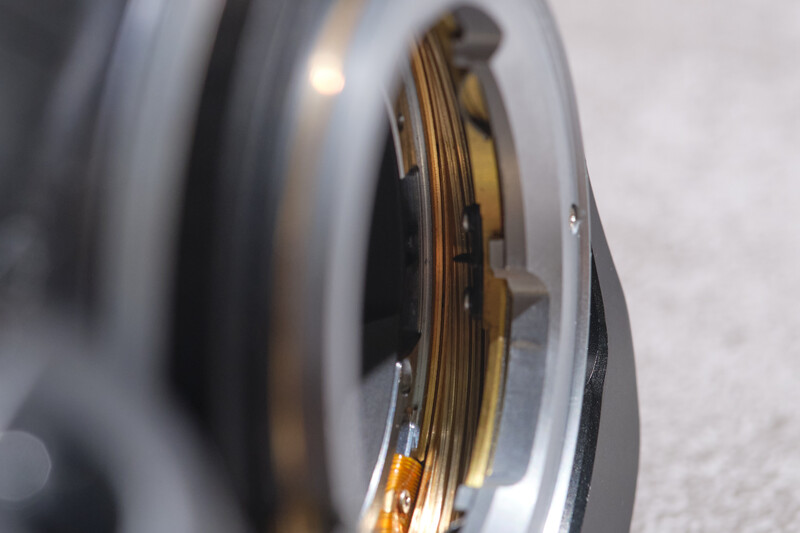 Close-up of camera lens elements showing internal glass optics and brass focusing helicoid threads
