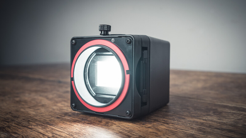Medium format camera with red-rimmed lens mount displayed on wooden surface