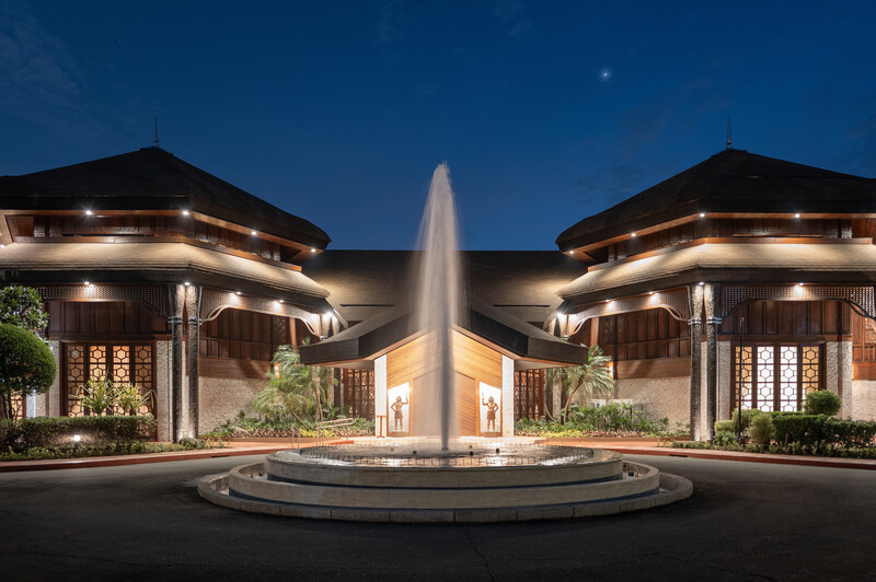 Symmetrical architectural night shot of two illuminated pavilion buildings flanking a central fountain