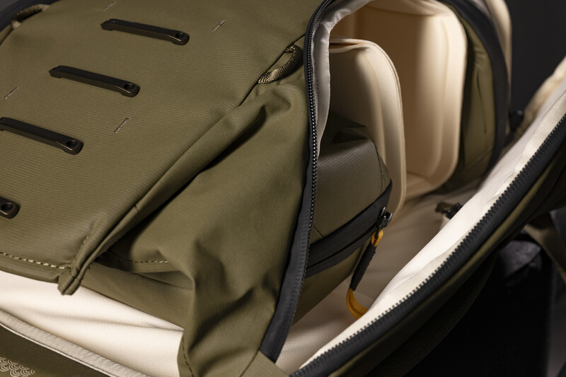 Open camera bag with olive and cream interior, showing headphones and protective padding