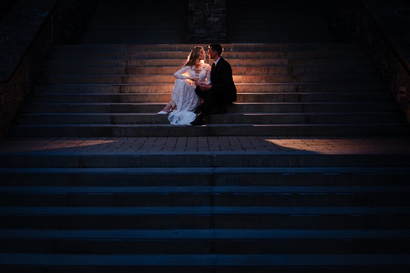 Couple embracing on illuminated steps at night with dramatic side lighting