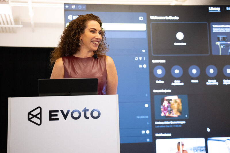 Woman speaking at podium branded with Evoto logo during presentation
