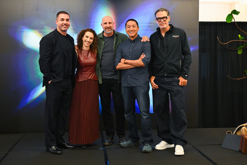 Five people posing together on stage with blue and purple stage lighting in background
