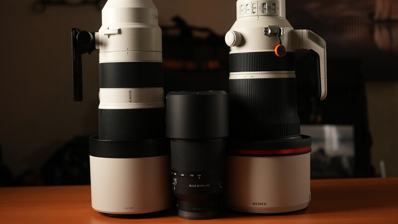 Three Sony telephoto lenses arranged side by side on a wooden surface