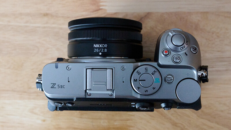 Nikon Z 5IIc mirrorless camera with Nikkor 26/2.8 lens mounted, viewed from above on wooden surface