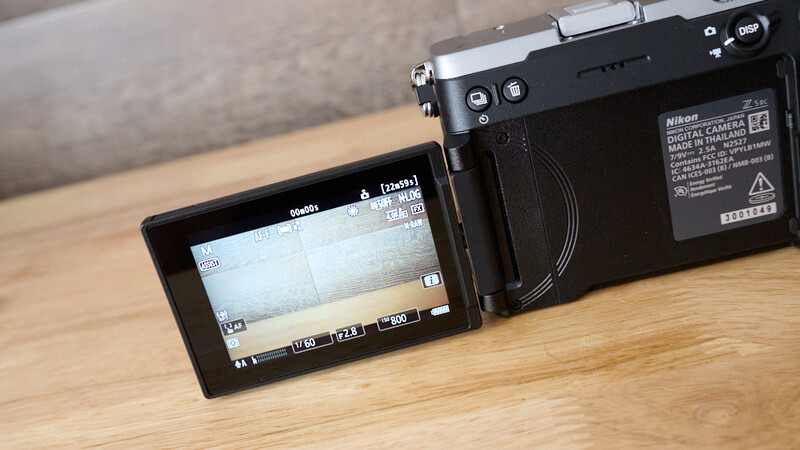 Nikon mirrorless camera with articulating LCD screen extended, displayed on wooden surface