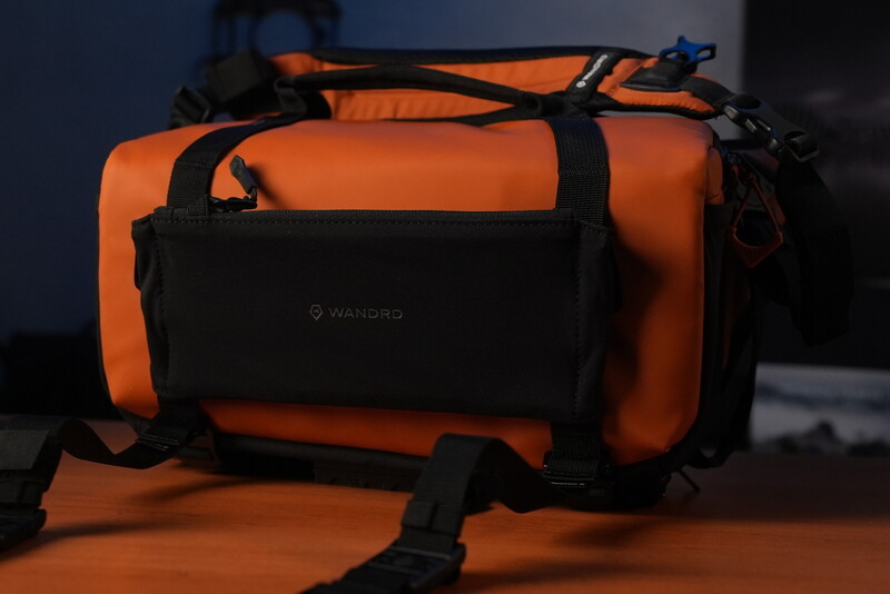 Orange and black weatherproof camera bag with multiple compartments and carrying straps