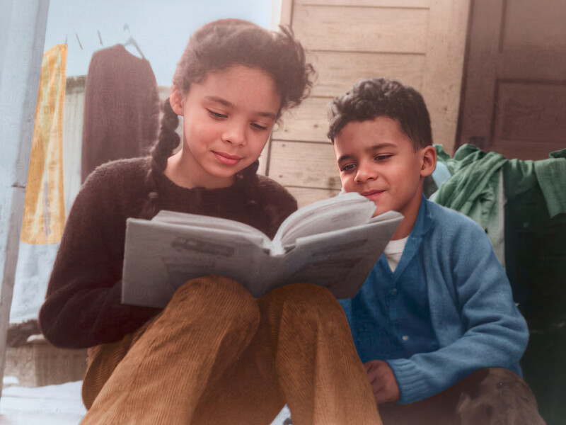 Two young children reading a book together indoors