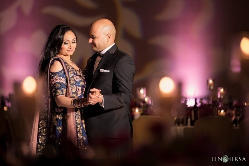 Couple in formal attire holding hands at an elegantly lit indoor event