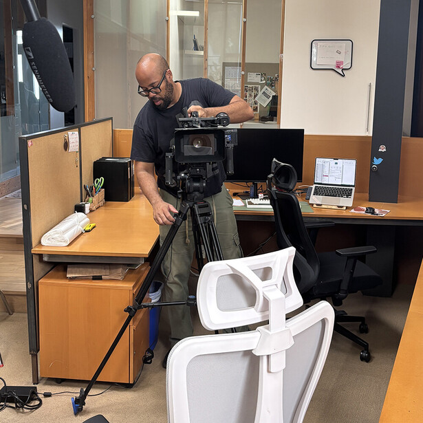 Cinematographer operating a professional video camera on a tripod in an indoor studio setting