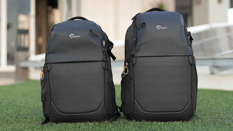 Two black camera backpacks with padded compartments displayed side by side on grass