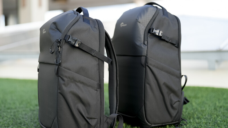 Two dark gray camera backpacks displayed side-by-side on grass