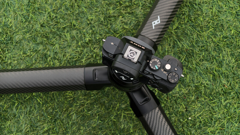 Mirrorless camera mounted on carbon fiber tripod head against artificial green turf