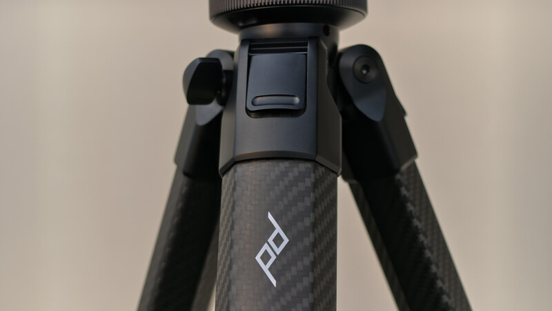 Close-up of carbon fiber tripod legs with black pan-tilt head and branded logo