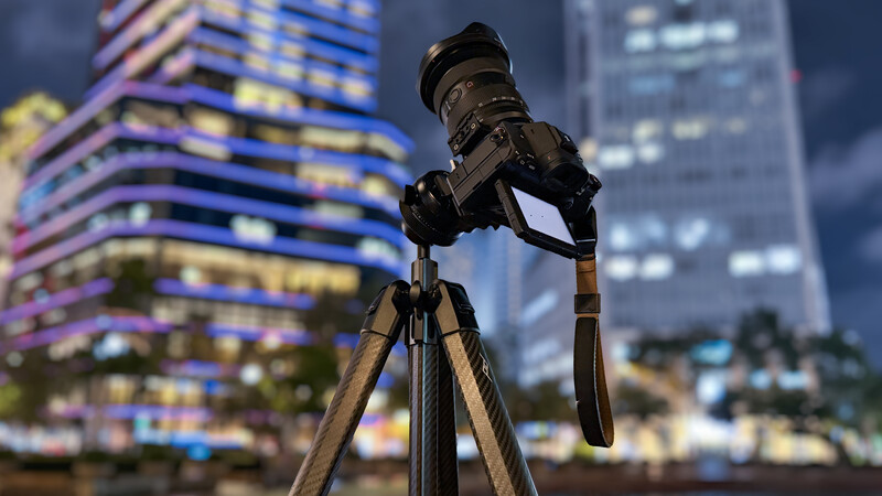Professional DSLR camera on tripod overlooking illuminated cityscape at dusk
