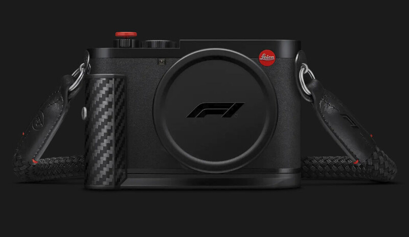 Black Leica compact camera with a carbon fiber hand grip and F1 logo on the lens cap, shown against a dark background.