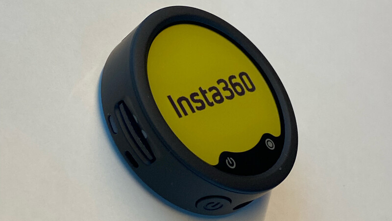 Insta360 compact device with a round yellow display and black body, photographed at an angle on a white background