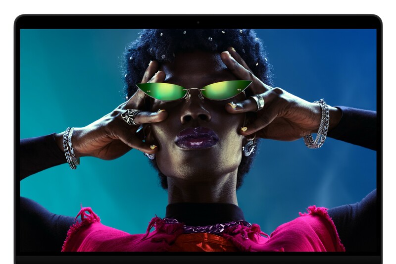 Person in green mirrored sunglasses with both hands framing their face, shown on a laptop screen against a teal backdrop