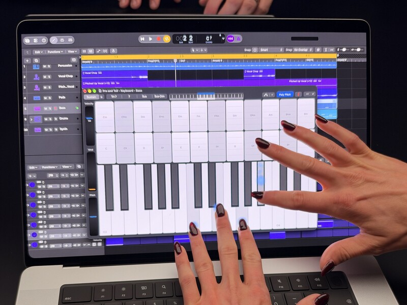Playing the onscreen keyboard with both hands in Logic Pro.