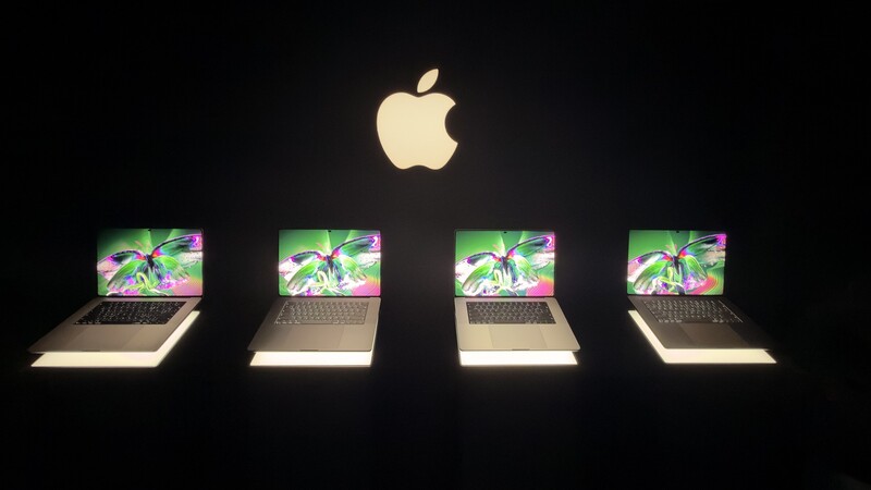 The new MacBook Pro models lined up under a glowing Apple logo in the demo area.