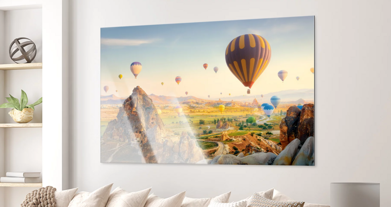 Hot air balloons floating above a landscape at sunrise, with striped balloon in foreground and multiple balloons scattered across misty valley.
