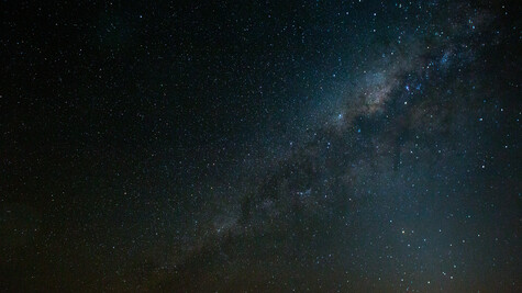 Milky Way galaxy stretching diagonally across a dark night sky filled with stars.