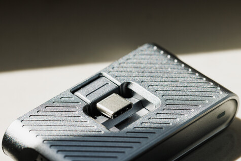 Close-up of a textured metallic flip phone with diagonal line pattern and chrome toggle switch.