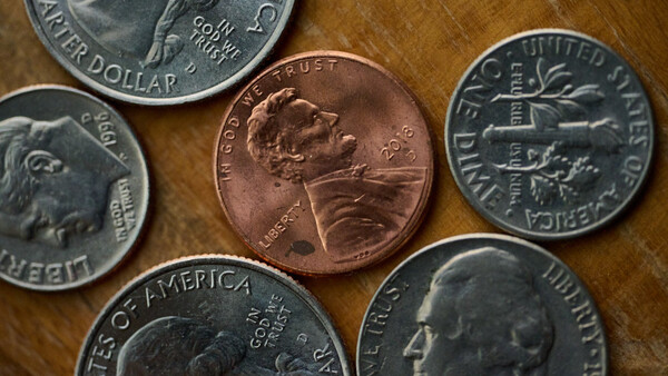 Assorted U.S. coins arranged on a wooden surface, including pennies, dimes, and quarters.