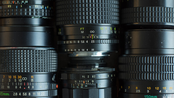 Overhead flat lay of vintage camera lenses with visible aperture and focus markings.