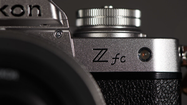 Close-up detail of a Nikon Zfc camera body showing the silver top plate with Zfc designation and control dial.