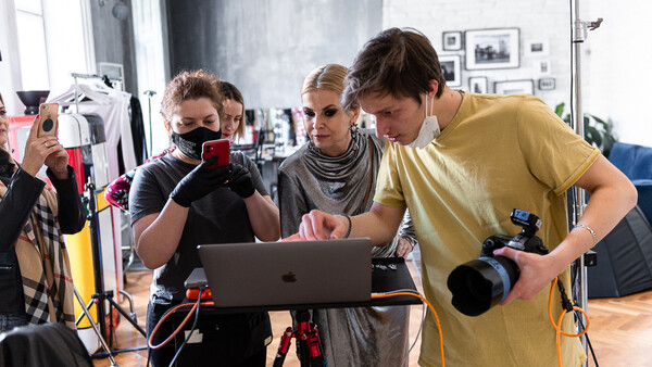 Group of photographers reviewing footage on a laptop during a studio production shoot.