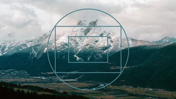 Nested geometric frames overlaid on a snow-capped mountain valley landscape with forested slopes.