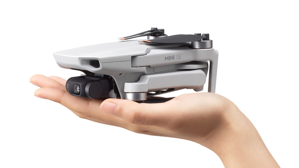 Compact drone with gray body and black camera module held in an open palm.