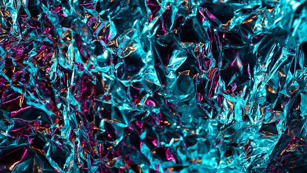 Abstract macro photograph of shattered glass or ice crystals with cyan, magenta, and dark tones.