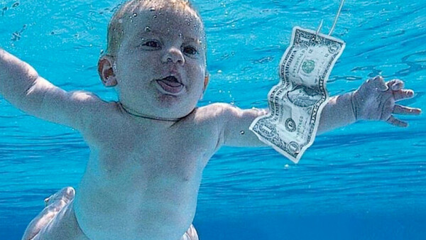 Infant underwater reaching toward floating dollar bills in pool.