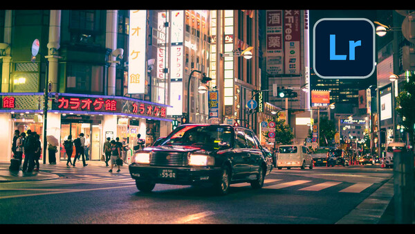 Taxi crossing a busy nighttime intersection in a Japanese city district with neon signs and pedestrians.