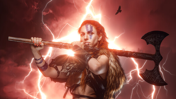 Warrior with red face paint holding an axe and staff across shoulders amid dramatic lightning and glow.