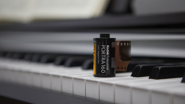 A roll of Kodak Portra 160 film positioned on a piano keyboard.