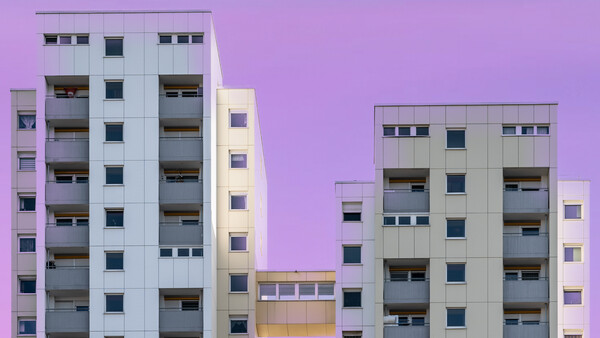Modern apartment buildings photographed against a vibrant purple twilight sky.