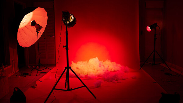 Professional studio setup with red-gelled lighting rigs creating atmospheric smoke effect.