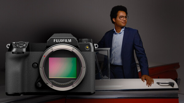 Fujifilm mirrorless camera with colorful sensor display next to standing professional.