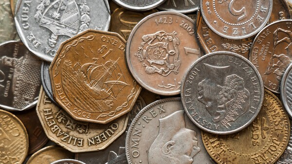 Overhead flat lay of mixed international coins in various metals and denominations.